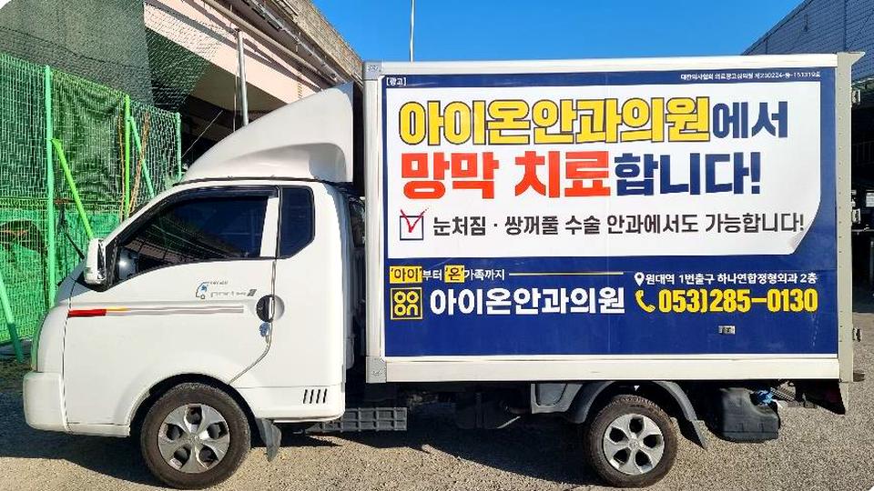 옆면 전체를 안과의원 광고로 랩핑한 택배 배송 차량