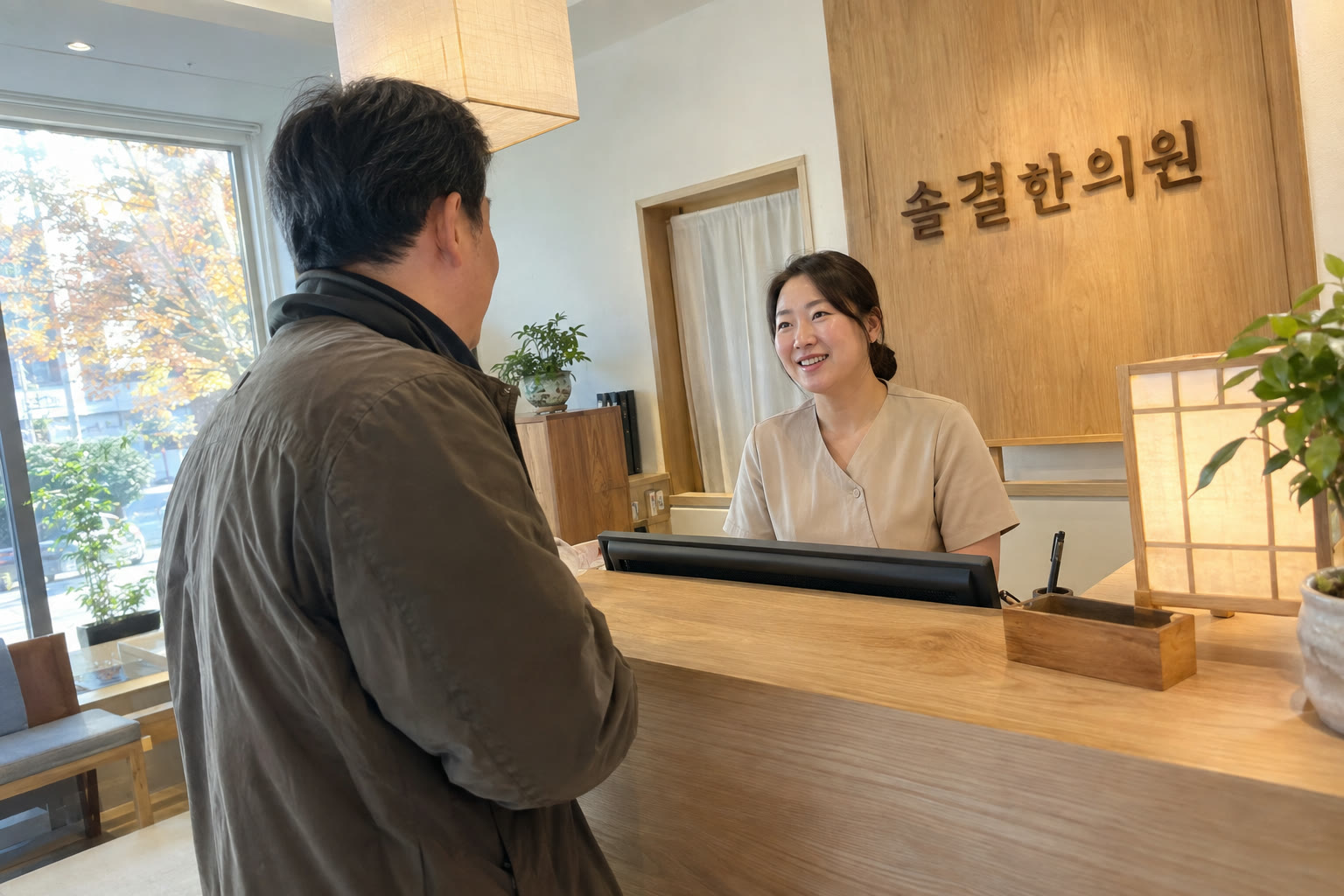 원목 접수 데스크에서 직원이 환자를 맞이하는 모습